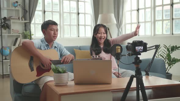 Asian Boy With Guitar And Girl Talking To Camera While Streaming