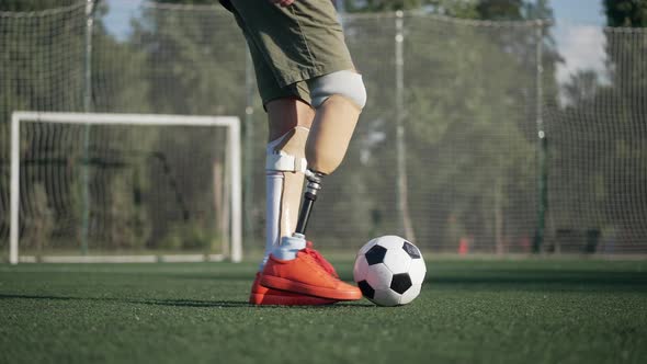 Side View Unrecognizable Amputee Playing with Soccer Ball in Slow Motion on Summer Sports Field