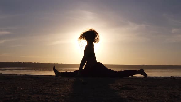 Young Woman Doing Split Yoga Posture Outdoors on the Beach