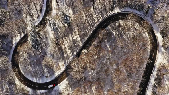 Timelapse of serpentine driving cars at a winter landscape filmed by a drone and a look up shot to a