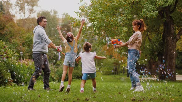 Parents and Kids Having Fun Together with Soap Bubbles in Summer Park