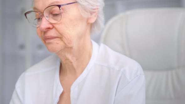 Exhausted senior woman pensioner takes off glasses and looks around relaxing