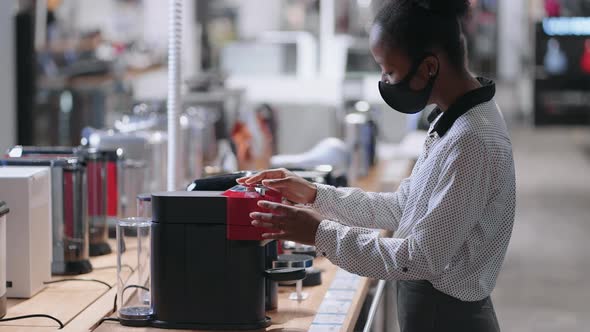 Young Lady is Shopping in Home Appliance Store Afroamerican Lady with Face Mask is Choosing