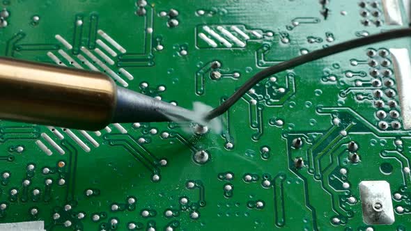 Close up shot electric solder in soldering on electronic print circuit board with hot lead