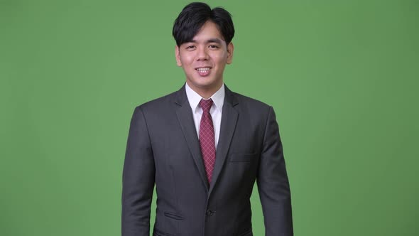Young Happy Asian Businessman Smiling While Talking To Camera