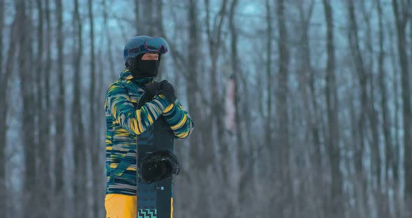 Snowboarder Leaned on a Snowboard and Looks Into the Distance