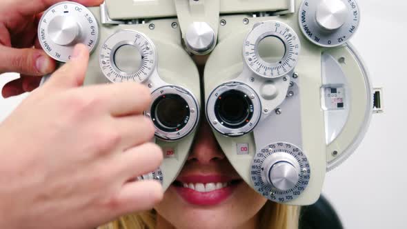 Optometrist examining female patient on phoropter