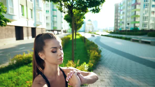 Young Woman Squatting Near Bench in City Street.