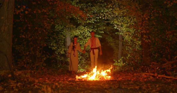 Couple of Lovers Jumping Over a Bonfire with Bare Feet in a Dark Forest the Customs of the Slavic