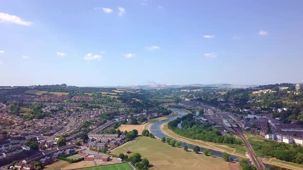 Aerial fly over of Exeter river and railway station tracks on blue summer day