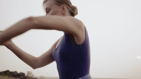 Caucasian ballerina emotionally dances with hands and arches back, outdoor. White dancer abruptly mo