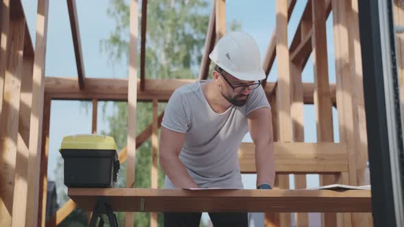 Man in a Helmet Works on a Construction Site, Draws a Blueprints