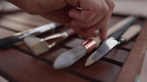 Closeup Female Hand Taking Round Painting Brush From Wooden Table
