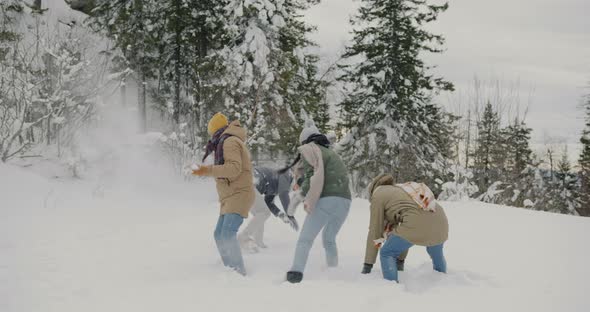 Excited Young People Playing Snowballs Outdoors in Winter Having Fun Together