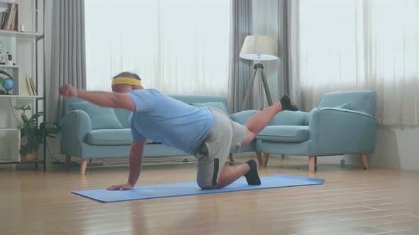 Fat Asian Man Doing Yoga In Balancing Table Pose On Mat  At Home