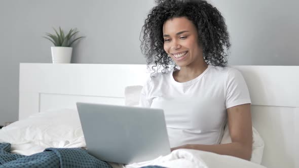 Online Video Chat on Laptop By African Woman in Bed