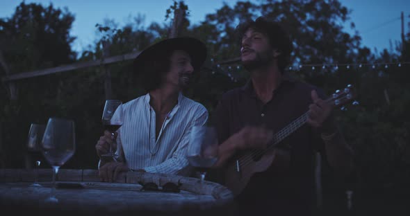 Two musicians playing guitar and drinking wine
