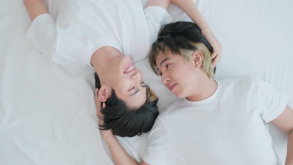 Asian young male gay family feel happy while lying down on bed in bedroom and look at each other.