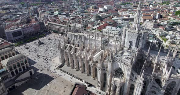 Ornate Milan Cathedral and masses of tourists on Piazza del Duomo; drone