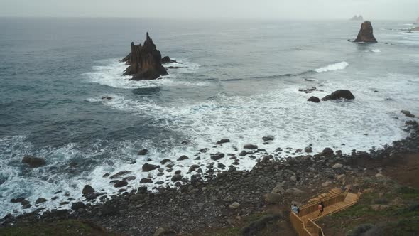 Young Man Tourist Goes Down the Long Stairs to the Famous Volcanic Black Sand Beach Benijo in the