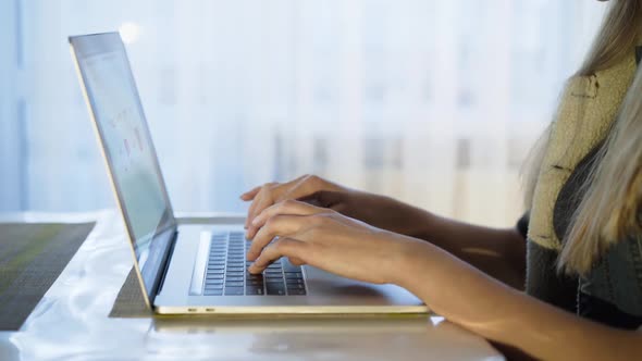 Female Hands Typing on Laptop Keyboard at Window