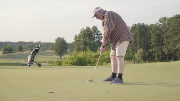 Cute Old Man Playing Golf Alone on the Golf Field