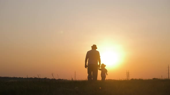 Two Generations Silhouette of a Mature Grandfather and Little Grandson Play at Sunset.