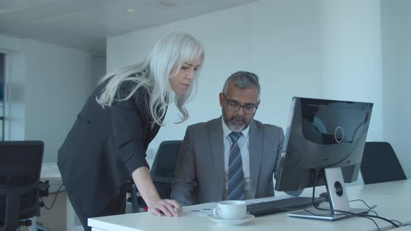 Serious Male Professional Explaining Reports To Female Boss