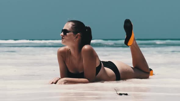 Young Woman in Black Bikini Tans on a Paradise White Sandy Beach Lies By Ocean