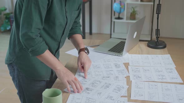 Designer Works On A Storyboard, Looks At His Sketches And Concepts, Choosing The Best Drawings