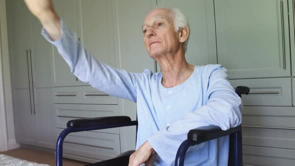 Senior man in wheelchair waving at home