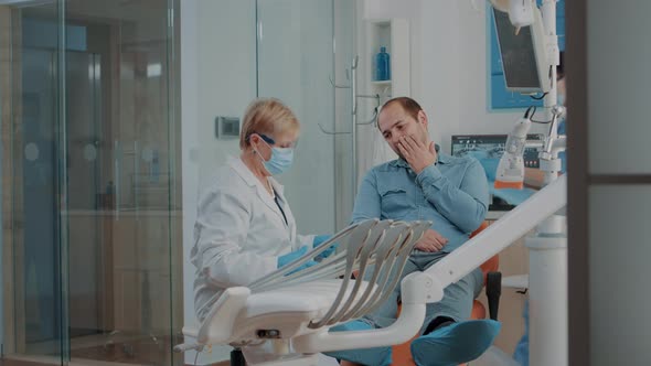 Dentist Looking at Dental x Ray and Consulting Patient with Toothache