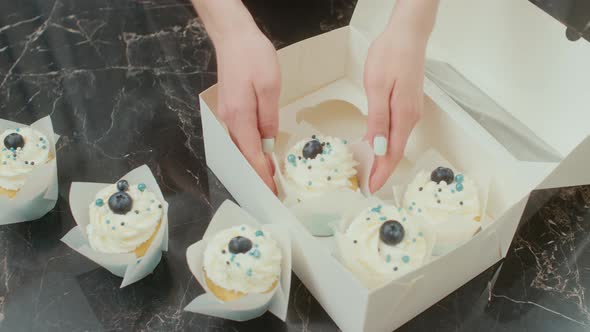 The Pastry Chef Puts the Cupcakes Into the Present Box on the Table