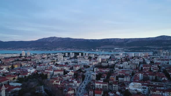 Vibrant city of Split with massive mountain range in background, aerial drone shot