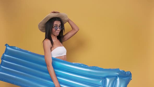Young African American Woman in Swimsuit with Inflatable Beach Mattress and Beach Hat on Yellow