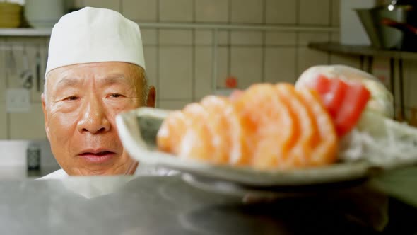 Male chef serving a plate with sushi in kitchen