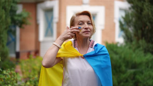 Medium Shot Portrait of Proud Ukrainian Woman Wrapped in National Flag Drawing Blue and Yellow on