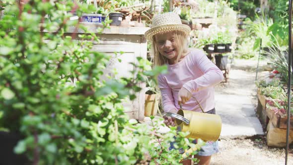 Little girl watering plants in a botanical garden