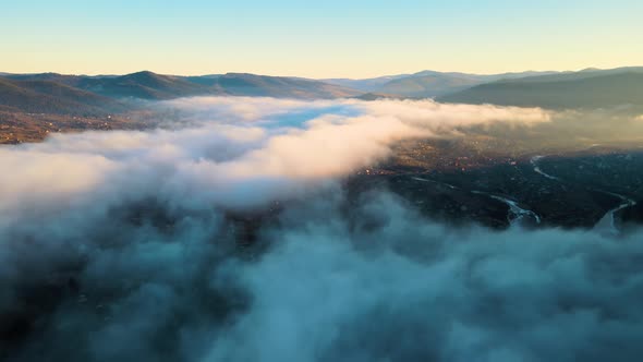 Aerial View of Moody Landscape of Foggy Clouds Covering Mountain Hills and Village Houses at Sunset