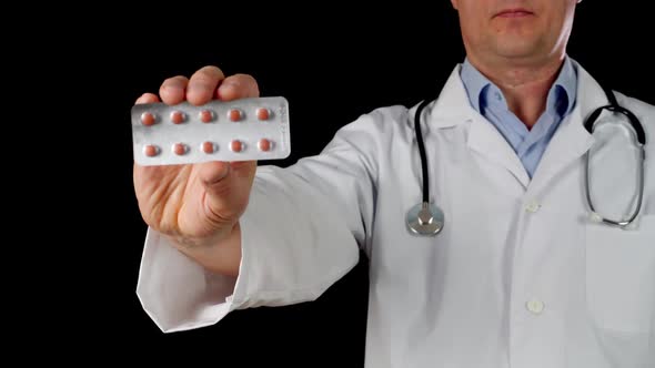 Doctor Hand in White Coat Holding Tablet Blister Front Camera Isolated on Black Background