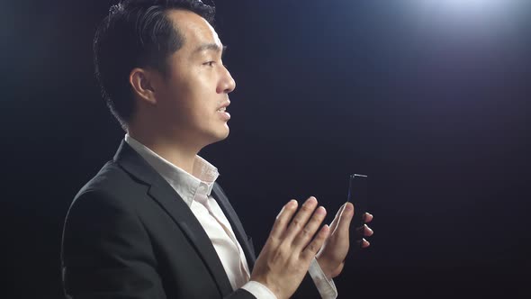 Close Up Side View Of Asian Speaker Man In Business Suit Pointing Smartphone While Speaking