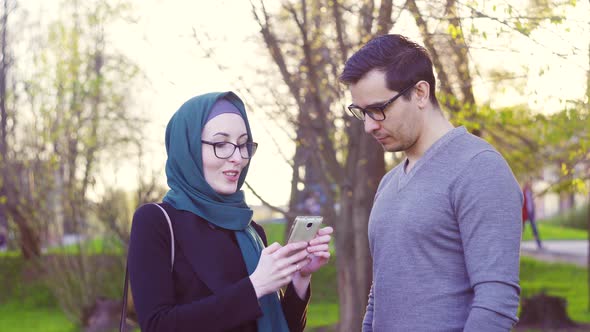 Guy and Girl in Hijab Talking on the Street in the Park