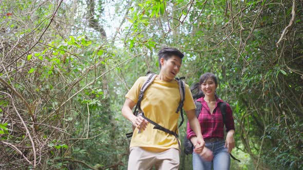 Asian young couple walk and travel in the forest, feel relax in nature wild, looking around the view