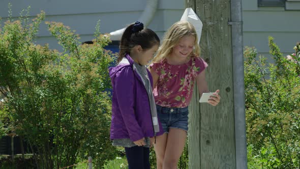 Young girls watching video on smart phone outside