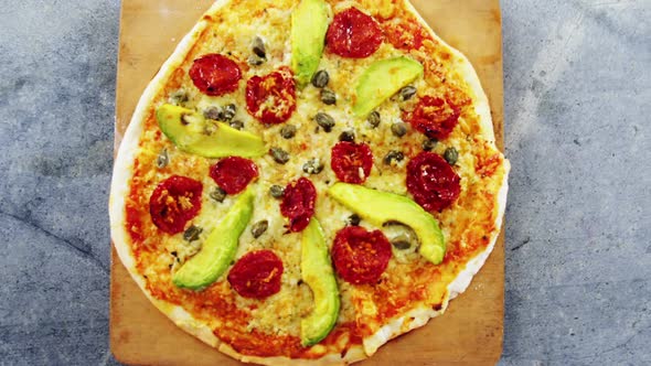 Baked pizza with avocado, cherry tomato and olive toppings