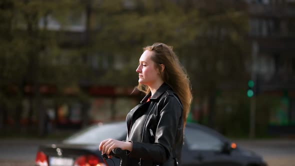 Young Stylish Woman Stands and Holds Electric Scooter in City Street