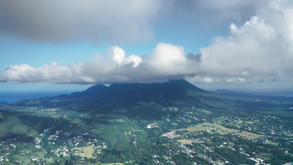 Drone camera moves over a city and rainforest near Nevis Peak in Saint Kitts and Nevis