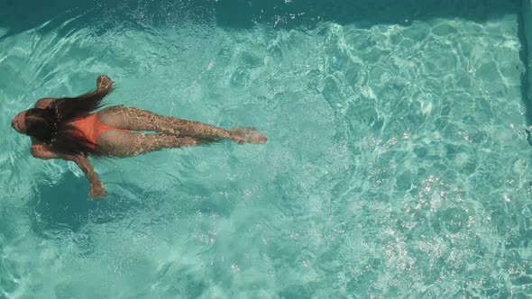 Attractive Young Female Swimming Alone in a Pool with Crystal Blue Water