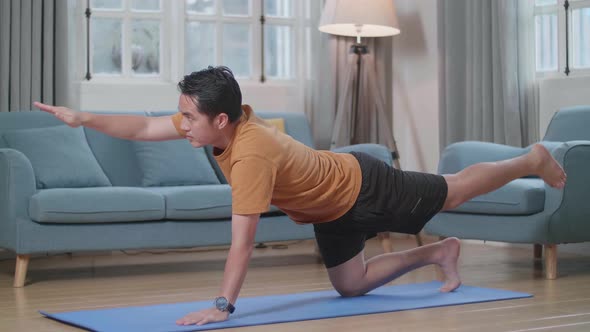 Asian Man Doing Yoga In Balancing Table Pose On Mat At Home