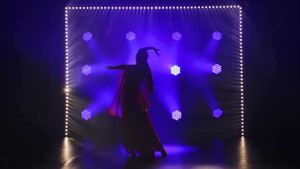 Silhouette a Young Girl Dancer in a Red Sari. Indian Folk Dance. Shot in a Dark Studio with Smoke